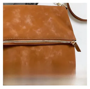 Macro shot of smooth metal zipper and premium caramel leather texture on shoulder bag