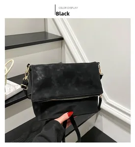 Detail of black matte suede shoulder bag with gold-tone metal zipper and hardware