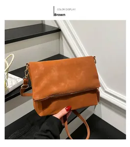 Detailed view of the brown leather envelope bag with gold hardware on stairs