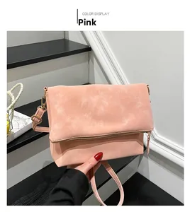 Detailed view of pink suede shoulder bag with gold zipper and adjustable strap