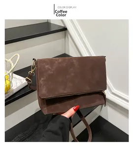 Detail of coffee brown matte saddle bag with gold hardware held on stairs