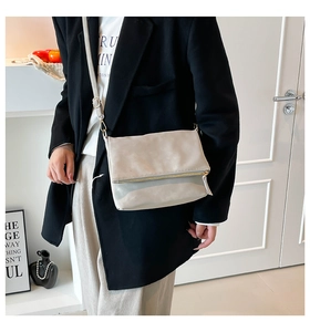 Detail of light beige pleated leather shoulder bag featuring a metal zipper and long strap