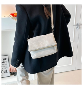 Close-up of light gray suede envelope crossbody bag with metal hooks on shoulder strap