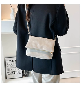 Detailed view of minimalist crossbody bag with fold-over design and gold zipper detail