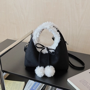 Détail du sac en daim avec bordure en fausse fourrure blanche, nœud noir et pompons