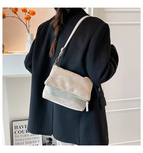 Detailed view of cream leather crossbody bag with gold zipper worn by model in a modern room
