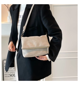 Detail of minimalist beige faux leather crossbody bag with premium gold metal zippers