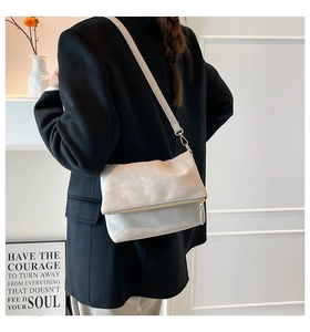 Chic light gray saddle crossbody bag displayed on a model in a minimalist studio setting