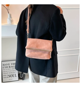 Detail of salmon pink crossbody bag with gold zipper and adjustable leather strap
