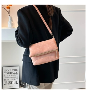 Detail of pink matte leather crossbody bag with flap and metal zipper on shoulder strap