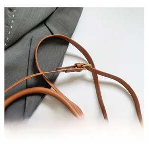 Detail of adjustable leather strap and golden hardware on brown saddle bag