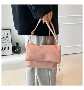 Detail view of pink matte vintage saddle bag with flap closure and gold metal hardware