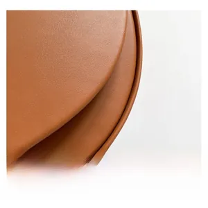 Detail of brown faux leather saddle bag showing premium stitching and lychee grain texture