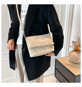 Detail of minimalist cream envelope crossbody bag with gold zipper and adjustable strap