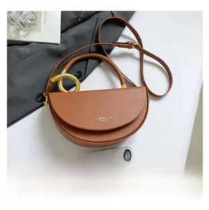 Brown semi-circle saddle bag detail showing gold circular handle and phone size reference