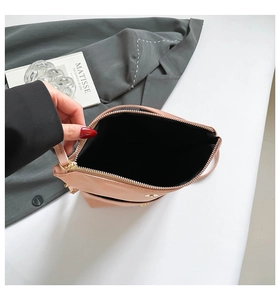 Detail of nude pink saddle bag with top zipper closure and gold-toned metal hardware