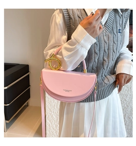 Detail of pink saddle bag featuring a unique gold metal knot handle and logo lettering