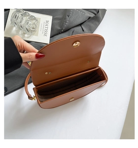 Detail of brown saddle bag showing striped lining and golden magnetic closure