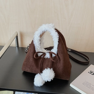 Détail du sac à main en daim marron foncé avec bordure en peluche blanche et pompons doux