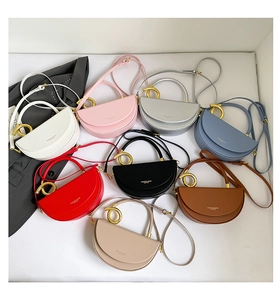 Macro view of multi-color leather saddle bags with round golden metal handles and straps
