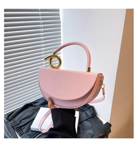 Detail of pink half-moon leather bag featuring gold abstract hardware and shoulder strap