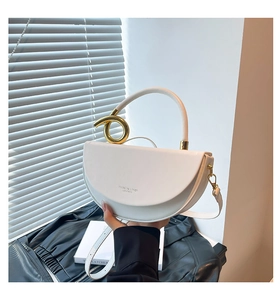Detail of white leather saddle bag with luxury interlocking gold circular handle and strap