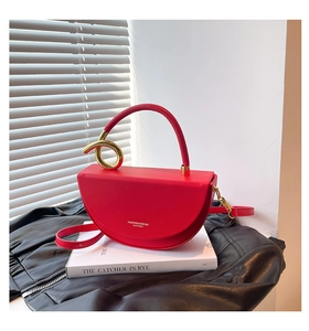 Detail of red leather half-moon bag featuring a unique gold twisted handle and strap
