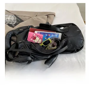 Spacious interior of black lychee leather bag showing tablet, notebook and accessories