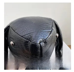 Close-up of black lychee grain faux leather on a rabbit-shaped backpack with metal accents