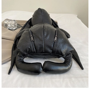 Detail of bunny-shaped black leather backpack showing litchi texture and metal zippers
