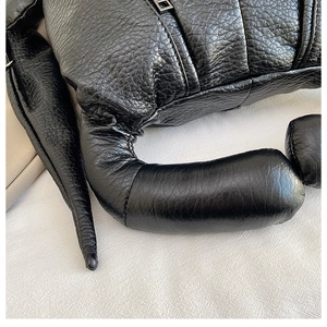 Close-up of black litchi grain leather texture and durable stitching on a backpack