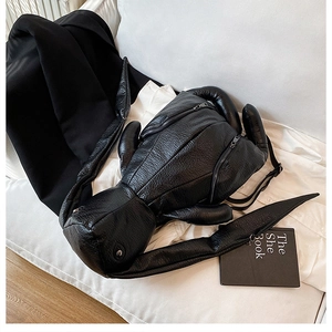 Detail of black rabbit shaped backpack with long ears and pleated faux leather texture