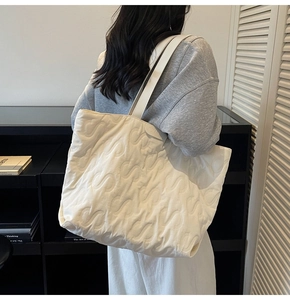 Detail of off-white quilted tote bag showing S-shape stitching and soft fabric texture