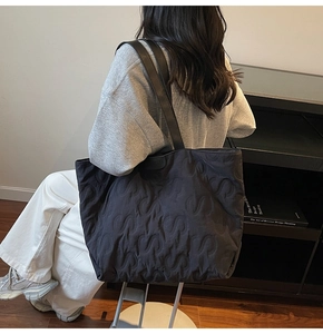 Detailed macro view of black quilted tote bag with S-shaped stitching pattern