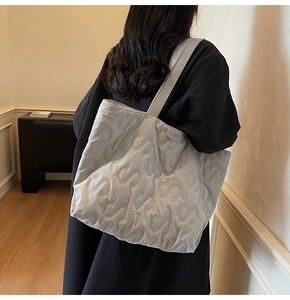 Detailed view of grey quilted tote bag with S-pattern stitching and leather shoulder straps
