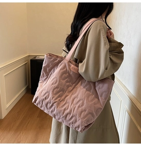 Close-up of pink quilted tote bag with S-pattern stitching and leather brand tag detail