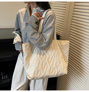 Detail of white quilted tote bag with S-shaped stitching texture and puffy fabric design