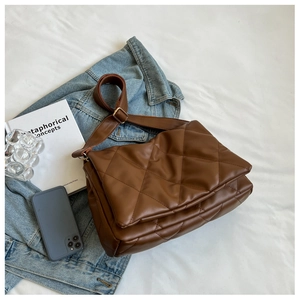 Detail of brown quilted leather crossbody bag with adjustable strap in casual setting