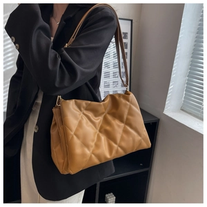Brown quilted tote bag styled as a shoulder bag on a model in a modern room setting