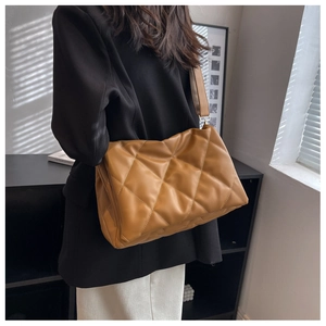 Detail of brown quilted shoulder bag with glossy finish and adjustable wide strap