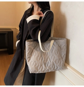 Detail view of light grey quilted tote bag with S-shaped stitching and wide textile straps