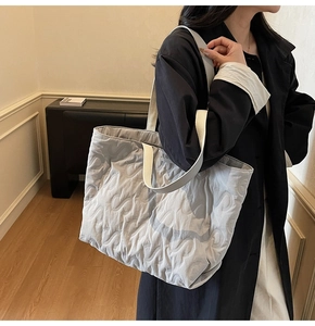 Close-up of light grey quilted tote bag featuring wave pattern and wide canvas strap