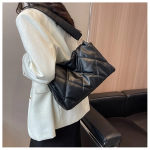 Detail of black quilted tote bag showing high-quality texture and gold buckle on shoulder strap