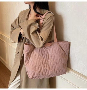 Detailed S-shaped quilting texture and brand logo on a soft lavender shoulder tote bag