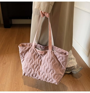 Close-up of pink quilted tote bag with S-shaped stitching and leather logo detail