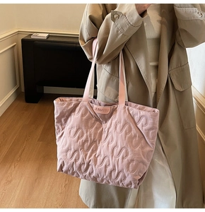 Detail of pink quilted tote bag showing intricate S-shaped stitching and leather logo brand