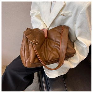 Detail of caramel quilted crossbody bag with adjustable wide shoulder strap on model