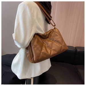 Brown quilted crossbody bag with large capacity worn with a white blazer