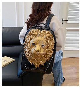Detail view of black leather backpack featuring a 3D gold lion head and silver rivets