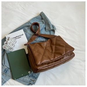 Brown quilted crossbody bag detail with wide shoulder strap and golden metal buckle adjustment